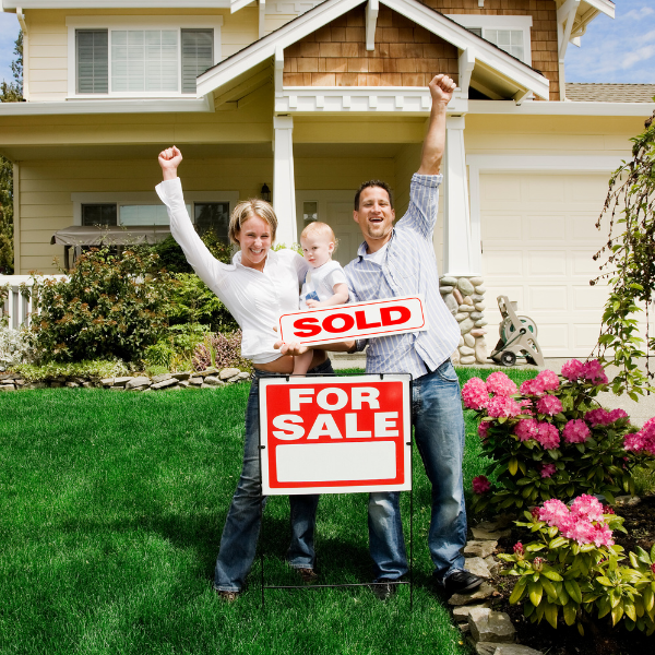 Picture of a happy homeowner in front of a sold house.